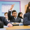Student raises his hand in a classroom
