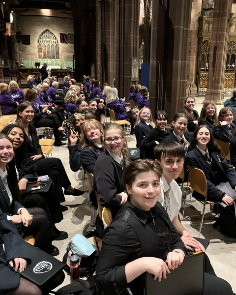 Group of students sitting in the cathedral smiling at the camera